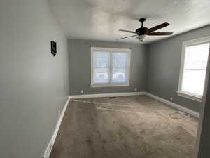 Empty room featuring carpet floors, a ceiling fan, and a textured ceiling
