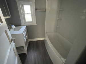 Bathroom featuring vanity, dark wood-style flooring, and washtub / shower combination