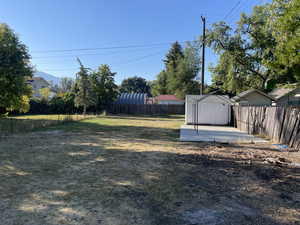 Fenced backyard featuring a storage unit