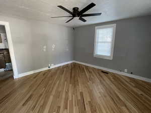 Unfurnished room featuring light wood-style flooring, a textured ceiling, and a ceiling fan