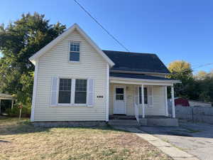 View of front of house with a porch, a front lawn, and a shingled roof