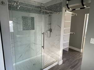 Bathroom featuring a marble finish shower and dark wood-style flooring
