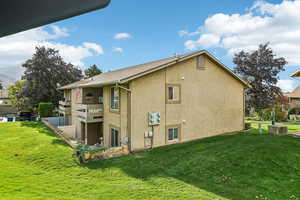 View of side of property with stucco siding, a yard, and a balcony