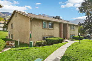 View of front of property featuring a mountain view, a front yard, and stucco siding