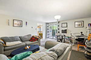 Living area featuring a textured ceiling, a desk, and wood finished floors