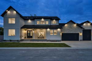 View of front of property with covered porch, stone siding, concrete driveway, board and batten siding, and a garage