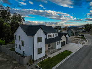Modern farmhouse featuring a shingled roof and driveway