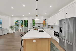Kitchen with stainless steel appliances, a kitchen breakfast bar, open floor plan, light stone counters, and recessed lighting