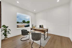 Office space with wood finished floors, recessed lighting, and a decorative wall