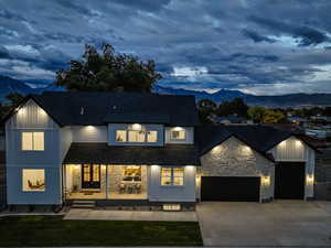 Modern inspired farmhouse featuring a mountain view, driveway, stone siding, and a shingled roof