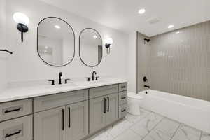 Full bath with bathtub / shower combination, double vanity, recessed lighting, and light marble finish floors