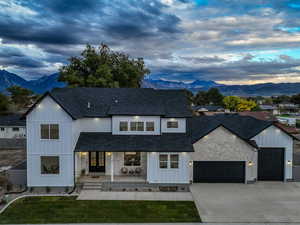 Modern farmhouse featuring a porch, a mountain view, an attached garage, and driveway