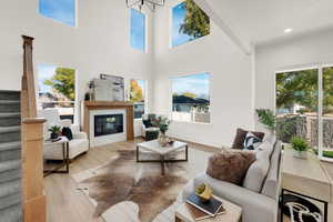 Living room featuring stairway, light wood-type flooring, plenty of natural light, a towering ceiling, and recessed lighting