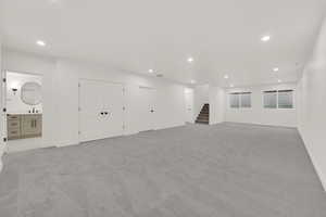 Basement with recessed lighting, light colored carpet, and stairs
