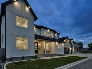 View of front of property with board and batten siding, driveway, a front lawn, and a garage