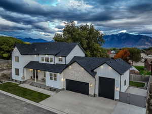 Modern farmhouse style home featuring a mountain view, covered porch, a gate, roof with shingles, and board and batten siding