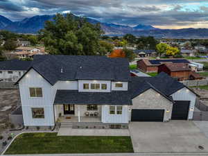 Modern inspired farmhouse with a porch, a shingled roof, a mountain view, board and batten siding, and a garage