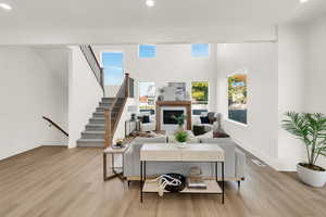 Living room with recessed lighting, a glass covered fireplace, light wood-style flooring, and stairway