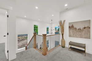 Hallway with an upstairs landing, carpet flooring, and recessed lighting