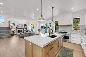 Kitchen featuring light stone counters, light wood-style floors, recessed lighting, decorative light fixtures, and white cabinets
