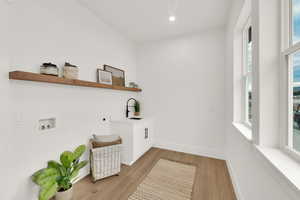 Washroom featuring hookup for a washing machine, light wood-type flooring, cabinet space, and recessed lighting