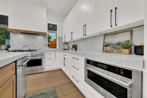 Kitchen with tasteful backsplash, stainless steel appliances, and white cabinetry