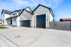 View of front of home featuring a gate, board and batten siding, stone siding, an attached garage, and driveway