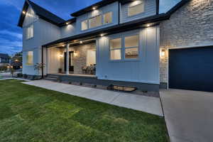 Entrance to property with stone siding, a yard, a garage, and board and batten siding