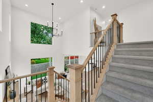 Staircase featuring healthy amount of natural light, a chandelier, recessed lighting, and a towering ceiling