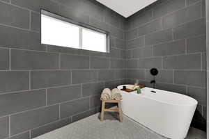 Full bathroom featuring a freestanding tub and tile walls