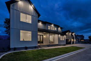 View of front of home featuring board and batten siding, a garage, driveway, and a lawn