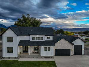 Modern farmhouse with a mountain view, covered porch, board and batten siding, and a shingled roof