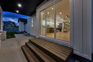 Property entrance with board and batten siding and a patio area