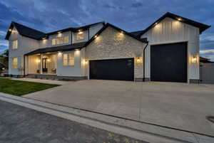 View of front of home with a garage, concrete driveway, board and batten siding, stone siding, and a porch