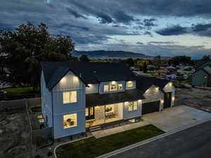 Modern inspired farmhouse with a mountain view, concrete driveway, a shingled roof, stone siding, and board and batten siding