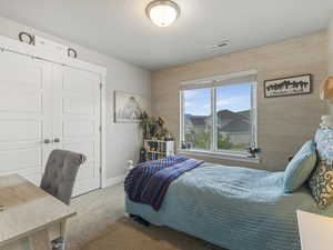 Carpeted bedroom with an office area, a closet, and wooden walls