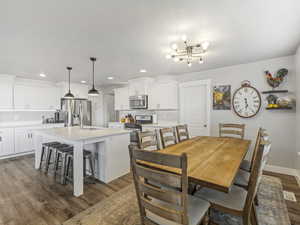 Dining area with dark wood-style flooring, a chandelier, and recessed lighting