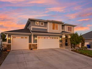 Prairie-style house with concrete driveway, stone siding, a garage, roof with shingles, and an attached garage