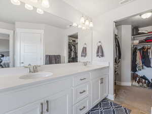 Primary bath featuring a spacious closet, double vanity, and light tile patterned flooring
