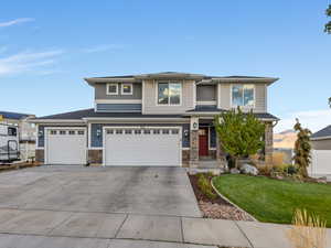 Prairie-style home featuring stone siding, driveway, and a garage
