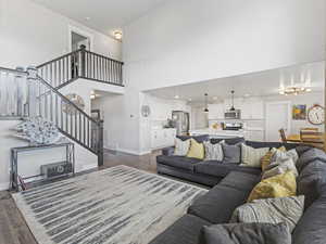 Living area with a towering ceiling, stairway, wood finished floors, and recessed lighting
