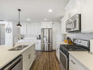 Kitchen featuring stainless steel appliances, pendant lighting, white cabinetry, dark wood finished floors, and recessed lighting