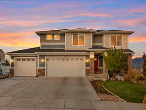 Prairie-style house with stone siding, concrete driveway, a yard, and roof with shingles