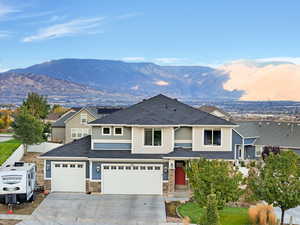 View of front of home with roof with shingles, concrete driveway, and a mountain view
