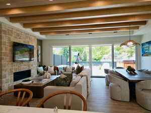 Living room featuring beamed ceiling, a fireplace, and wood finished floors