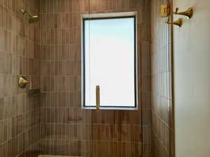 Bathroom featuring a tile shower and healthy amount of natural light