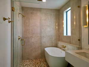 Bathroom with healthy amount of natural light, a shower stall, a soaking tub, vanity, and tile walls