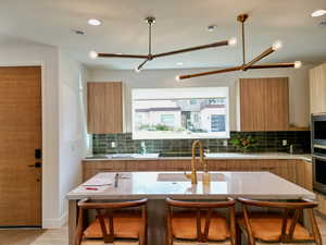 Kitchen with modern cabinets, a breakfast bar, backsplash, and recessed lighting