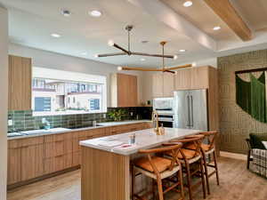 Kitchen with light wood-style flooring, a kitchen bar, tasteful backsplash, modern cabinets, and appliances with stainless steel finishes
