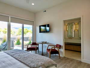 Bedroom with access to outside, light wood-style floors, ensuite bathroom, and recessed lighting